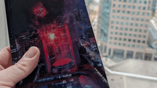 Hand holding a small photo zine in front of a city skyline.